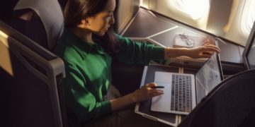 Passagier in British Airways Business Class werkt op laptop