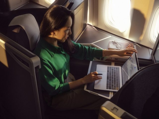 Passagier in British Airways Business Class werkt op laptop