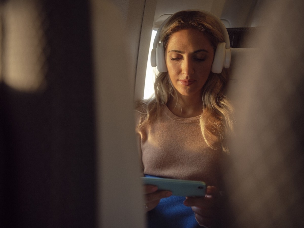 Passagier in British Airways Economy Class kijkt op telefoon